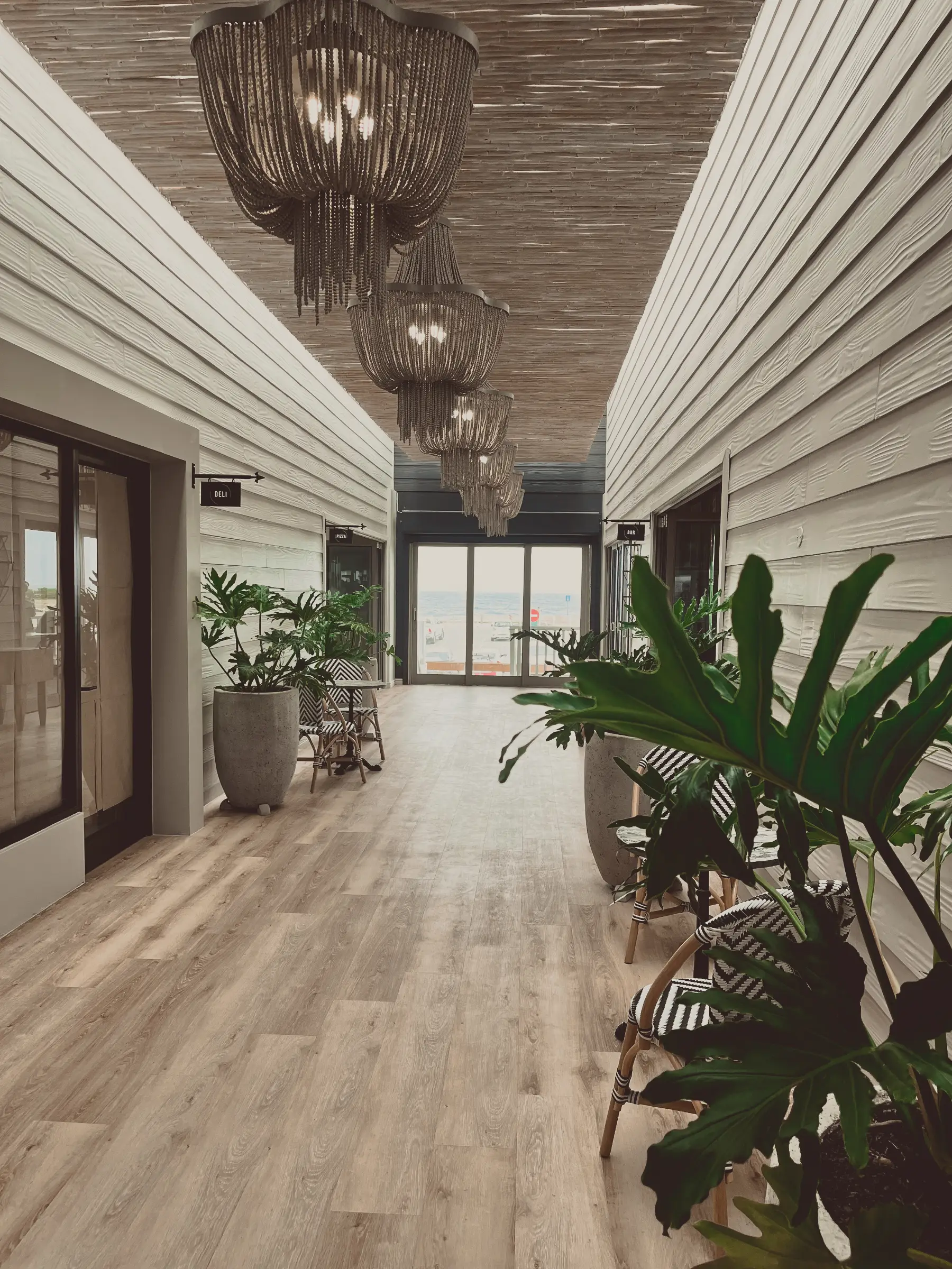 A renovated hallway from the Glentana project featuring stylish light fixtures, wood laminate flooring and indoor plant decorations.
